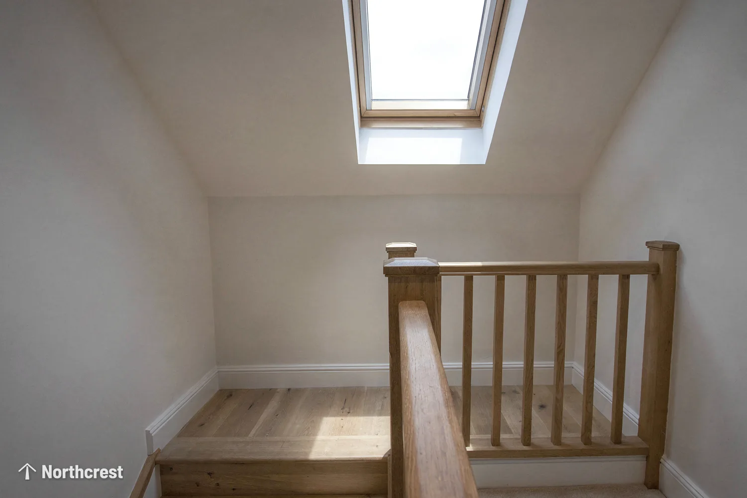 Loft stair landing with oak banister brightened by a pine pitched roof window