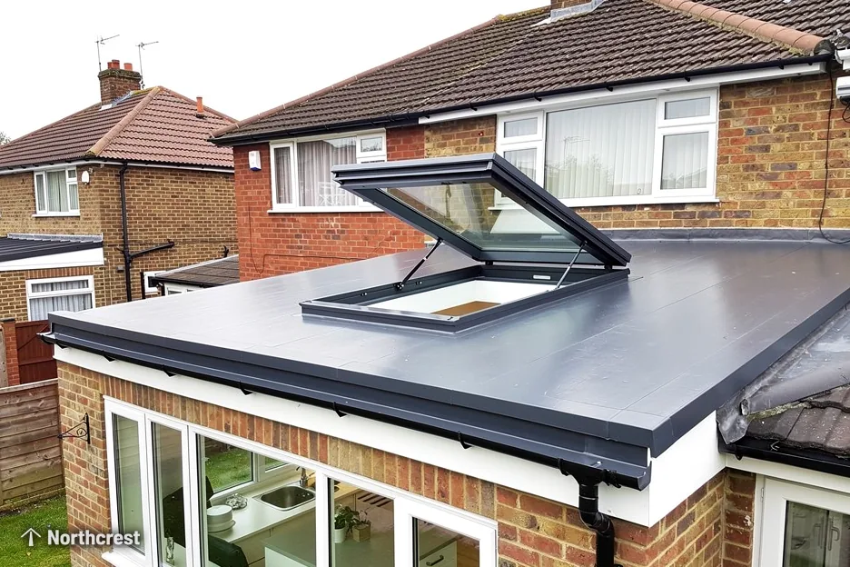 Opening flat rooflight raised on its arms on a grey flat roof of a brick extension