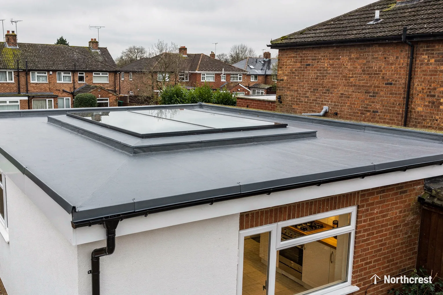 Twin pane flat rooflight on a grey single-ply roof of a rendered brick extension
