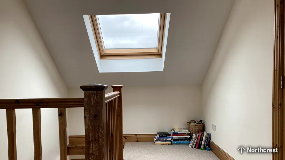 Loft landing with timber banister lit by a pine pitched roof window set in the sloping ceiling